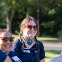 group of four GVSU alumni smile and laugh with each other